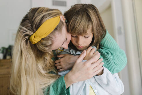 Mother embracing depressed daughter from behind at home - TYF00400