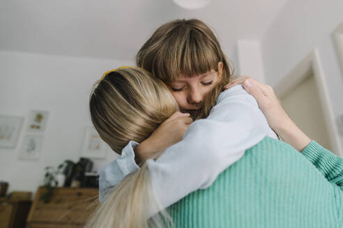 Depressed daughter embracing mother at home - TYF00402