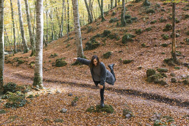 Lächelnde Frau balanciert auf einem Felsen in Fageda D'en Jorda, Olot, Girona, Spanien - MMPF00279