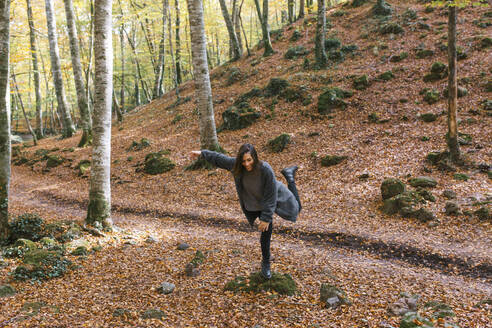 Smiling woman balancing on rock at Fageda D'en Jorda, Olot, Girona, Spain - MMPF00279