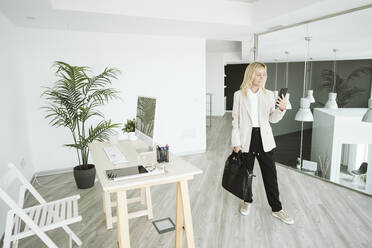 Geschäftsfrau in einem modernen Büro mit Mobiltelefon - EBBF06136