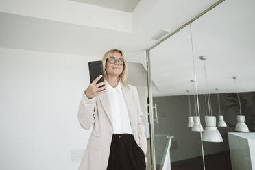 Geschäftsfrau in modernem Büro mit Mobiltelefon - EBBF06150