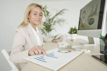 Businesswoman working on a chart at desk in office - EBBF06161