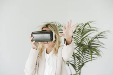 Businesswoman wearing VR goggles in office - EBBF06195
