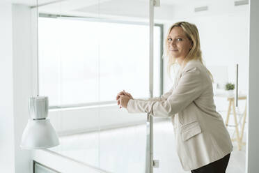 Geschäftsfrau lehnt an Geländer in minimalistischem Bürokorridor - EBBF06219