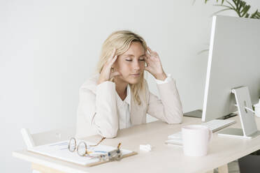 Tired businesswoman sitting at desk in office - EBBF06243
