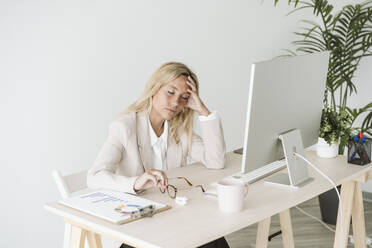 Müde Geschäftsfrau sitzt am Schreibtisch im Büro - EBBF06244