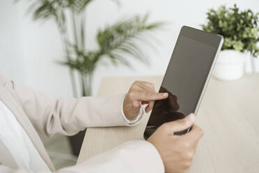 Close-up of businesswoman using tablet PC at desk in office - EBBF06252