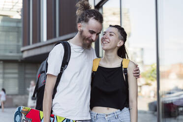 Happy hipster man with arm around non-binary person - OSF00847