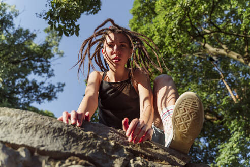 Young non-binary person climbing on stone wall - OSF00866