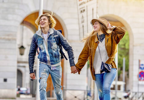 Carefree couple holding hands on vacation walking in city - GGGF01103