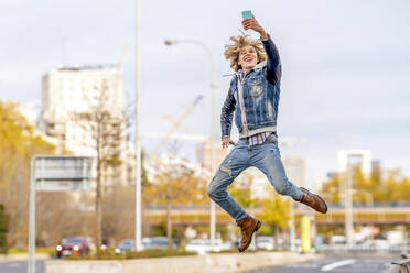 Glücklicher Mann springt und nimmt Selfie durch Smartphone - GGGF01117