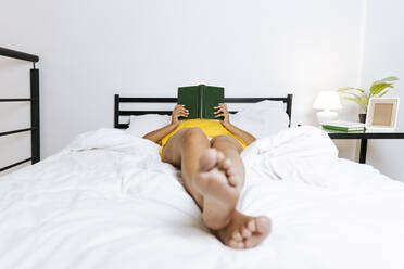 Frau liegt auf dem Bett und liest ein Buch - SIF00394