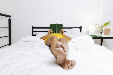 Woman lying on bed and reading a book - SIF00394