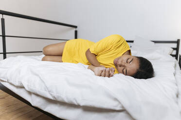 Exhausted woman in yellow t-shirt sleeping on bed at home - SIF00423