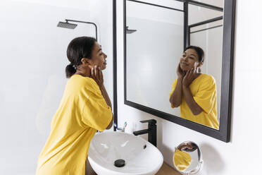 Frau betrachtet sich im Badezimmerspiegel - SIF00425