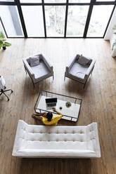 Woman sitting in living room floor working from home using laptop, elevated view - SIF00449