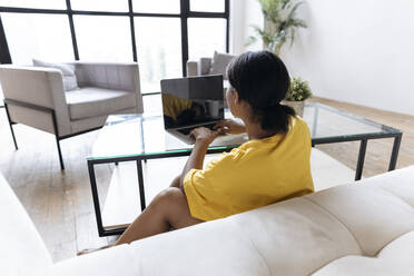 Woman sitting in living room working from home using laptop - SIF00451