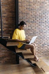 Frau, die auf einer Treppe sitzend an einem Computer arbeitet - SIF00459