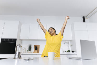 Glückliche Frau, die sich in der Küche streckt und eine Pause vor der Arbeit macht - SIF00479