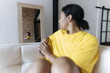 Eine Frau sitzt auf einem Sofa und schaut in den Spiegel - SIF00487