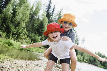 Happy brothers wearing hats at riverbank - VBUF00139