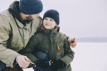 Lächelnder Junge in warmer Kleidung sieht seinen Vater im Winter an - MASF31462