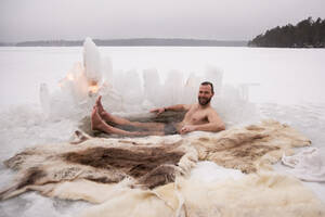 Porträt eines glücklichen reifen Mannes, der ein Eisbad auf einem zugefrorenen See genießt - MASF31504