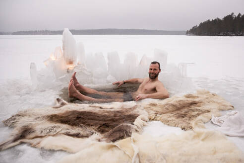 Portrait of happy mature man enjoying ice bath at frozen lake - MASF31504