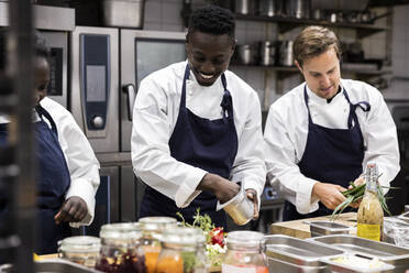 Chefs talking while preparing food in restaurant kitchen - MASF31543