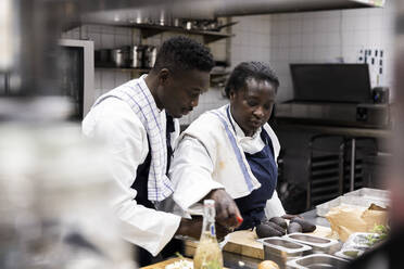 Männliche und weibliche Köche bei der Zubereitung von Speisen in der Restaurantküche - MASF31546