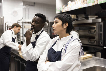 Männliche und weibliche Kollegen beim Brainstorming in der Restaurantküche - MASF31582