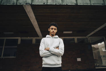 Portrait of young man wearing hoodie with his arms crossed stock