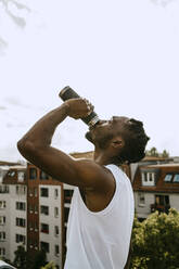 Side view of young man drinking water against sky - MASF31723