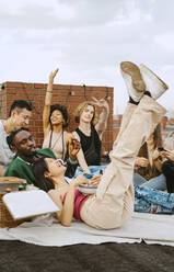 Glückliche männliche und weibliche Freunde genießen zusammen auf dem Dach - MASF31755