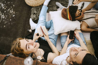 High angle view of male friends sitting by woman lying down - MASF31762