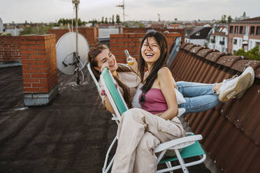 Fröhliche Frauen, die auf einem Stuhl auf dem Dach sitzen und genießen - MASF31776