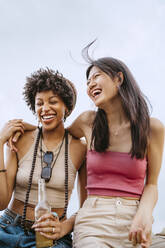 Fröhliche junge Frauen, die lachend vor dem Himmel sitzen - MASF31789