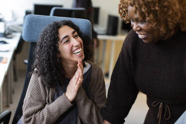 Happy businesswoman discussing with colleague in office - MASF31828