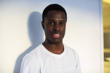 Portrait of teenage boy standing against white wall - MASF31846