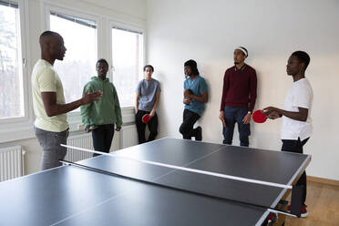 Instructor giving table tennis training to students in games room - MASF31852