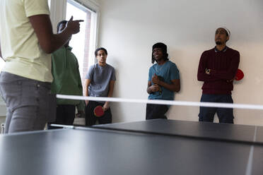 Schüler nehmen an einem Tischtennistraining unter Anleitung eines Lehrers im Spielsaal teil - MASF31853