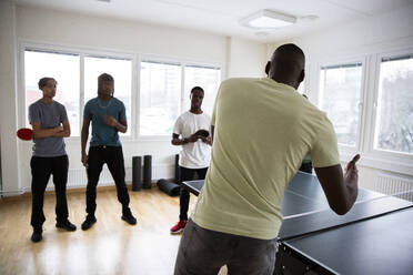 Rear view of coach conducting training sessions with students in games room - MASF31858