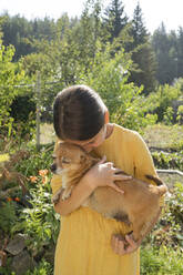 Mädchen umarmt Hund im Garten an einem sonnigen Tag - LESF00103