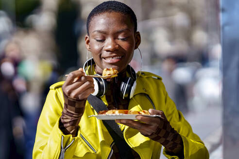 Woman holding plate eating food from spoon - GGGF01154