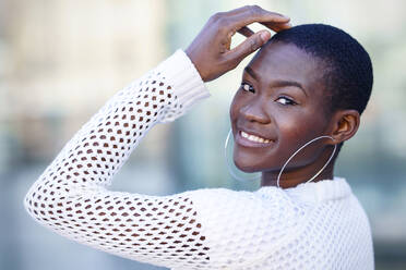 Smiling woman with head in hand wearing hoop earrings - GGGF01187