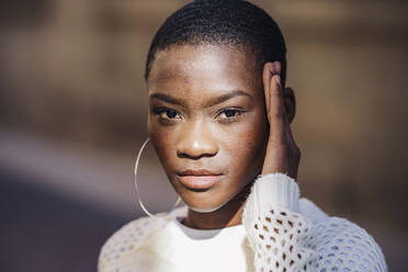 Woman touching head wearing hoop earrings on sunny day - GGGF01194