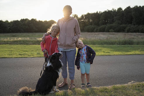 Mutter mit Töchtern und Hund stehen zusammen - DWF00587