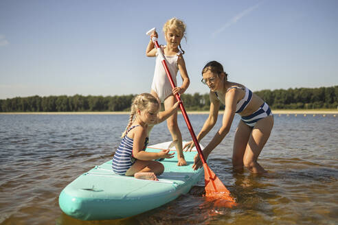 Mädchen mit Mutter auf Stand Up Paddle Board inmitten des Sees - DWF00590