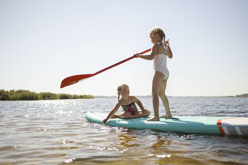 Mädchen haben Spaß auf dem Stand Up Paddleboard am See - DWF00591